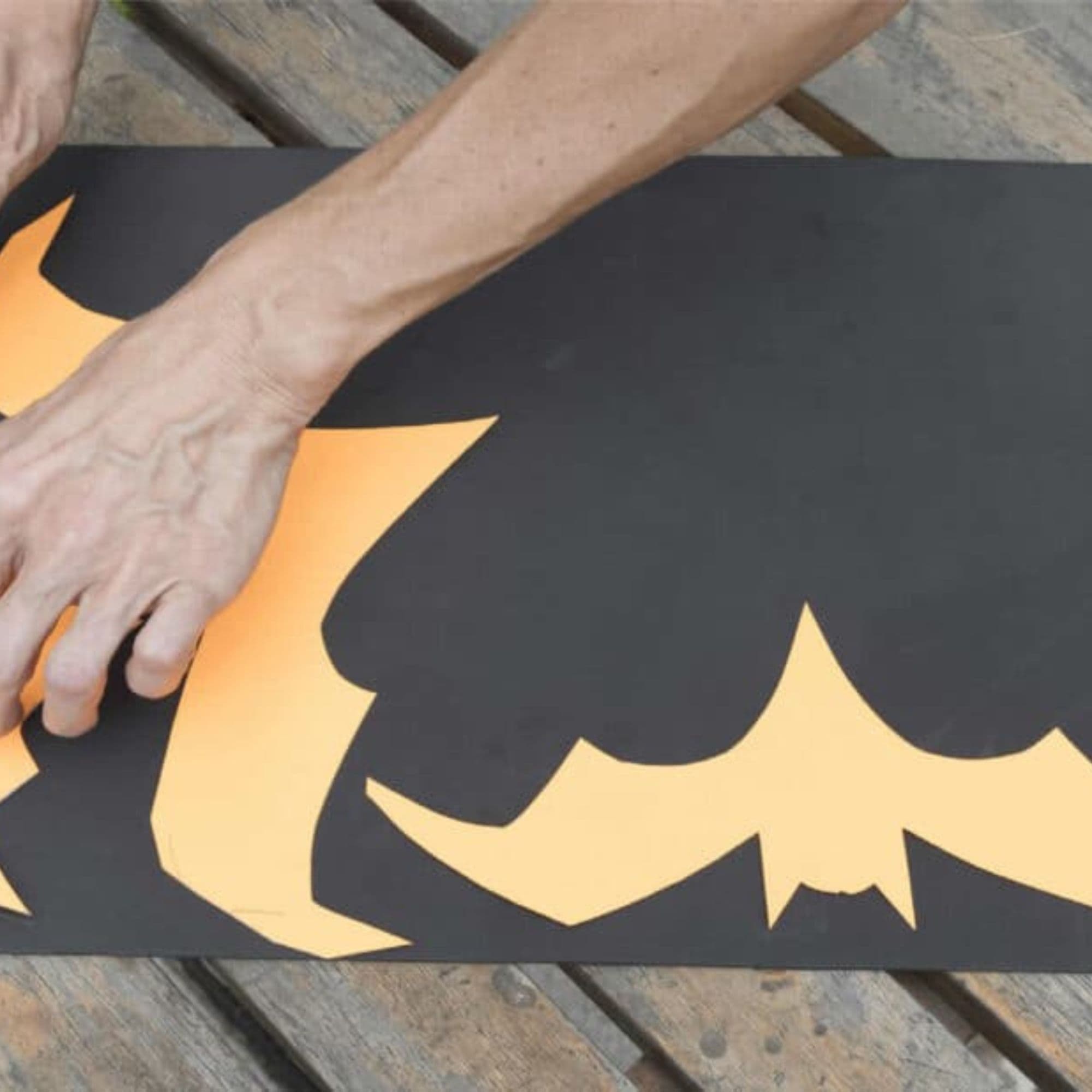 Serena cuts out orange bat shapes on a black foam sheet.