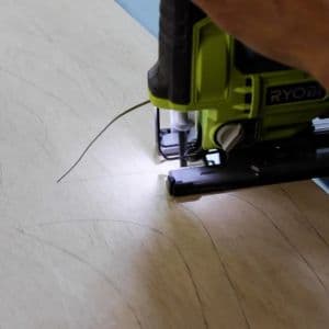 Serena uses a jig saw to cut out the shape of the spider on the wood.