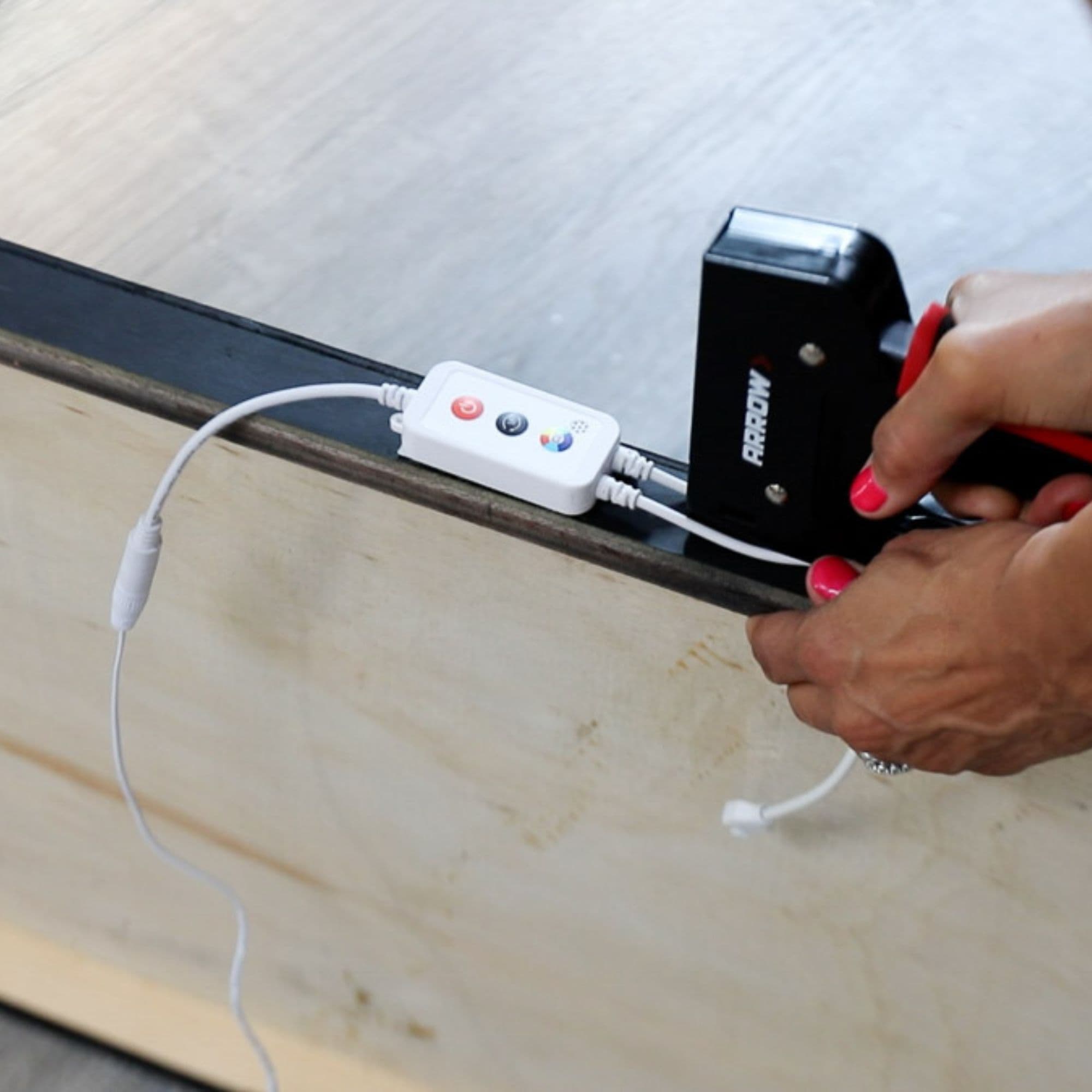 Serena staples an LED wiring switch to her gazebo using a staple gun.