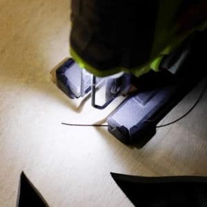 Serena uses a jig saw to cut out the shape of the spider on the wood.