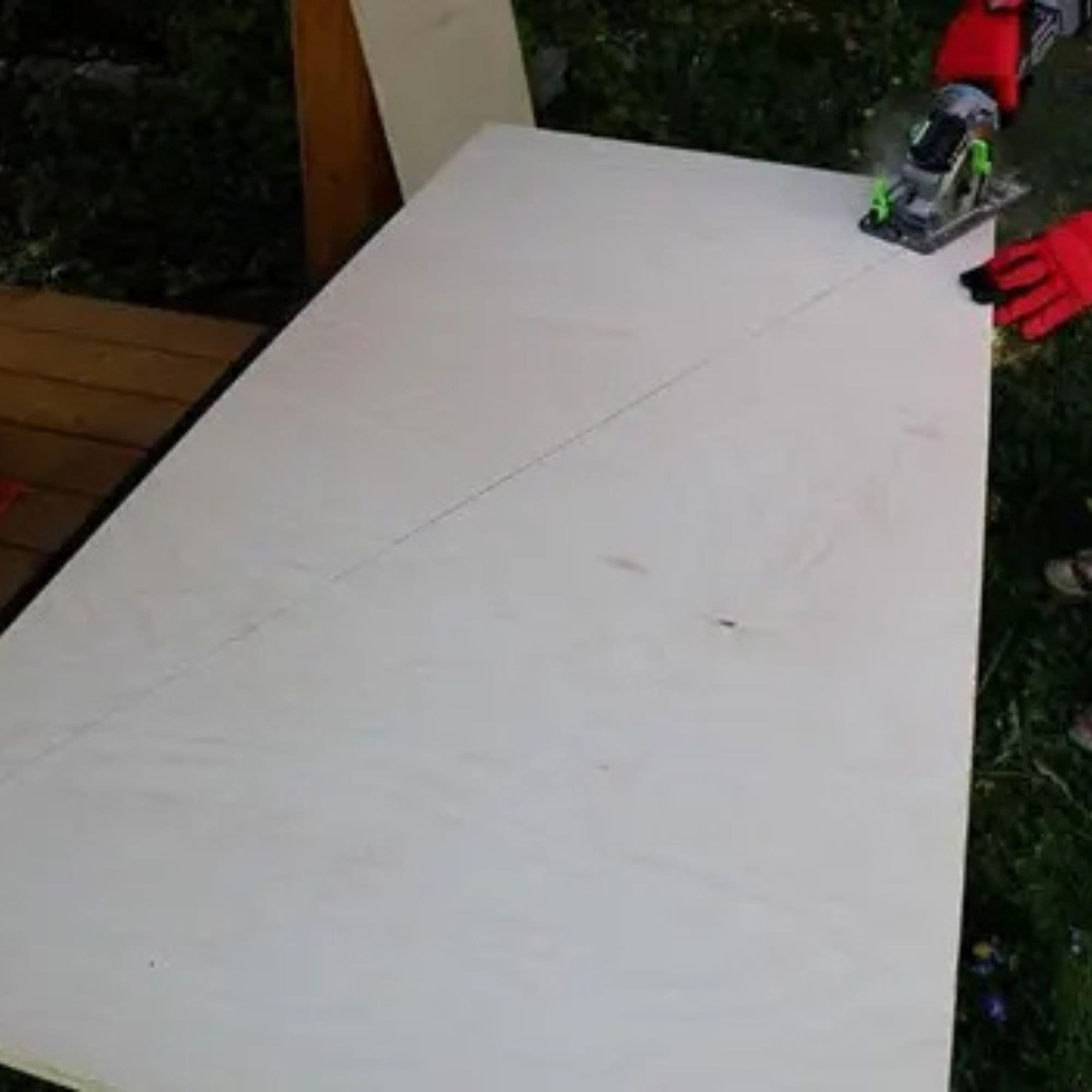 Plywood sheet marked with a diagonal cut line, circular saw resting on top